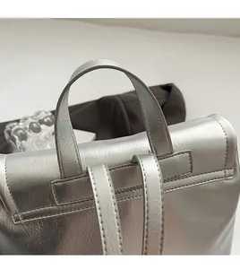 Dettaglio del manico rinforzato e trama in pelle argentata di uno zaino alla moda