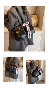 Detail of black bowling tote bag with pebbled texture and red-white ribbon decoration