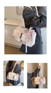 Detail of off-white tote bag featuring dual front pockets and plaid lace charm