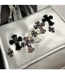 Dettaglio borsa argento con toppe a croce in materiali misti e borchie metalliche
