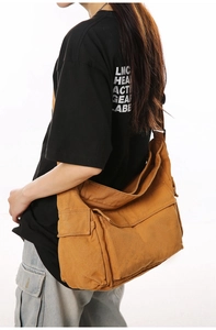 Detail view of khaki canvas crossbody bag with side pocket flap on female model