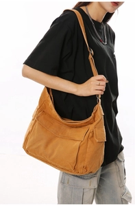 Detail view of large mustard canvas crossbody bag with multiple utility flap pockets