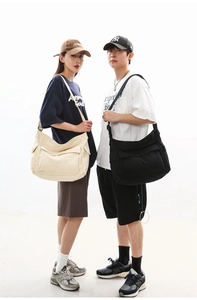 Detail of large canvas crossbody bags in black and beige with adjustable wide straps