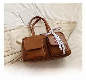 Close-up of brown PU leather shoulder bag with two front pockets and lace ribbon detail