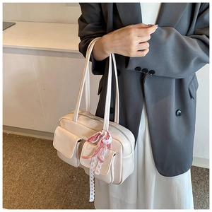 Detailed view of beige bowling bag with multiple pockets and decorative lace ribbon