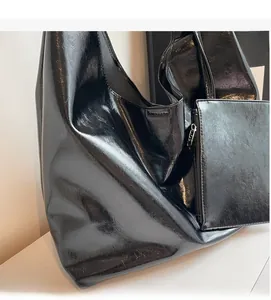 Close-up of black glossy PU leather tote bag with a matching small zipper pouch
