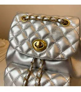 Vue détaillée d'un sac à dos en cuir matelassé argenté avec fermoir doré et chaîne