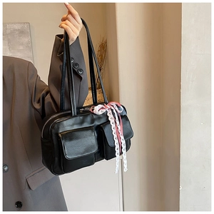 Detail of black bowling bag featuring cargo pockets and a vintage lace ribbon detail