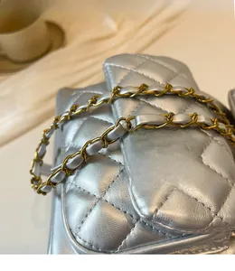 Détail macro du sac à dos argenté matelassé avec finition métallisée et chaîne bicolore