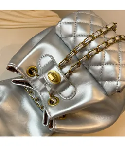 Détail du sac à dos argenté matelassé avec cordon de serrage et chaîne dorée