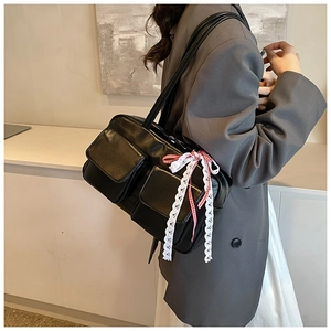 Detail of black vintage leather tote bag with lace bow charm and front flap pockets