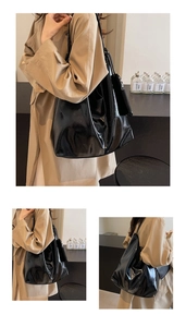 Detail of a large black tote bag in glossy leather showing texture and soft shoulder strap