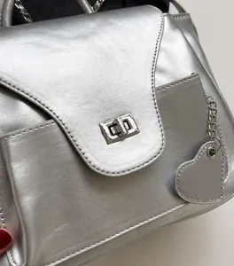 Détail du sac argenté en similicuir métallisé avec pendentif en forme de cœur