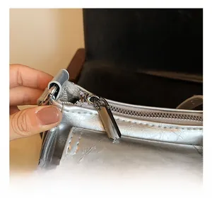 Macro shot of polished silver zipper and metallic textured leather on a chic shoulder bag