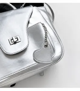 Détail du sac argenté avec pendentif en forme de cœur et fermoir rotatif en métal