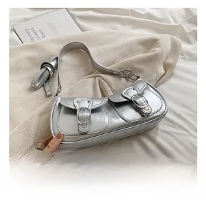 Detail of silver metallic Y2K shoulder bag featuring dual buckle pockets and wrinkled texture
