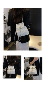 Detail of white quilted mini backpack with gold-tone twist lock and woven chain strap