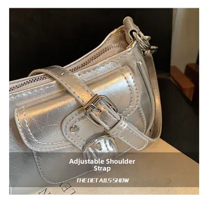 Detail of adjustable buckle strap on a silver metallic textured motorcycle hobo bag