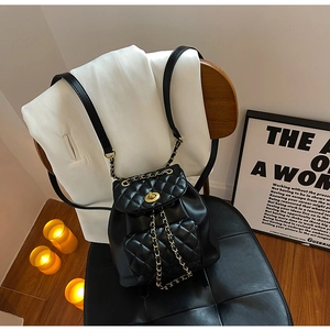 Détail du sac à dos matelassé noir avec sangles en chaîne dorée et fermoir rotatif