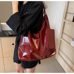 Detail of dark red glossy faux leather tote bag with small matching zipper pouch charm