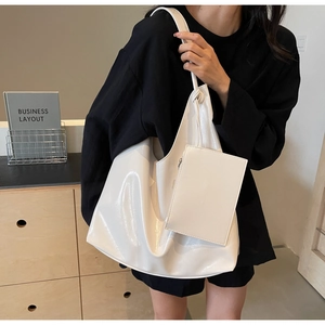 Glossy white tote bag with knotted handle detail and matching pouch for daily commute
