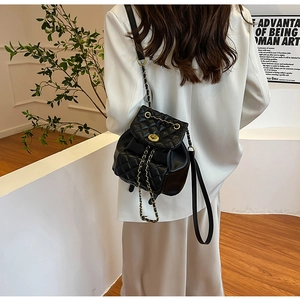 Mannequin portant un mini sac à dos noir matelassé avec fermoir doré et bandoulière chaîne