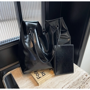 Glossy black patent leather tote bag set with wide shoulder strap and matching clutch