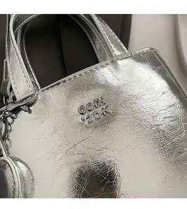 Détail du sac seau argenté miroir avec texture froncée et logo métallique COIH 2DN