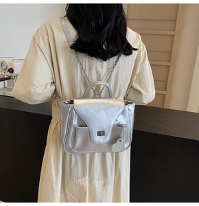 Détail du sac argenté en cuir métallisé avec breloque cœur et fermoir rotatif sur chaîne