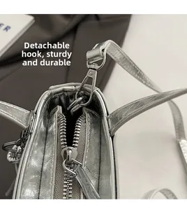 Détail d'un sac à main argenté métallisé avec fermeture éclair et crochet amovible
