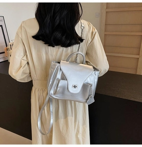 Détail du mini sac à dos argenté métallisé avec breloque cœur et fermoir rotatif
