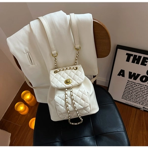 Détail d'un mini sac à dos blanc matelassé avec fermoir doré et bandoulière chaîne