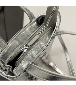 Gros plan sur la fermeture éclair en métal et le cuir argenté texturé du sac seau