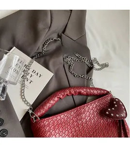 Détail du sac seau rouge en cuir PU tressé avec chaîne argentée et breloque en cœur