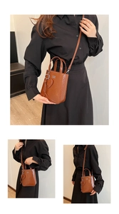 Détail d'un sac bandoulière en cuir huilé marron avec poignée et breloque coeur
