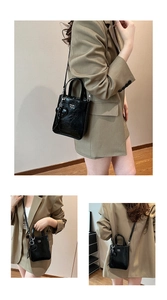 Détail du sac bandoulière en cuir brillant noir avec breloque cœur et lettrage blanc