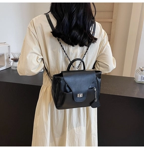 Vue arrière d'un sac à dos en similicuir noir avec chaîne argentée porté par un modèle