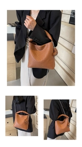 Détail du sac cabas tressé marron avec chaîne argentée et breloque coeur à rivets