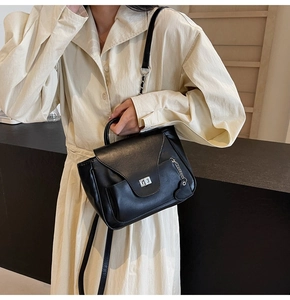 Détail d'un sac à main noir avec fermoir rotatif argenté et pendentif en cœur