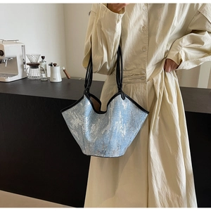 Detail der hellblauen Pailletten-Tasche mit gewelltem Rand und schwarzen Schulterriemen