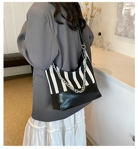 Close-up of black and white striped shoulder bag with silver chain on model