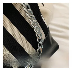Detail of chunky silver metal chain strap on contrast striped canvas and leather bag