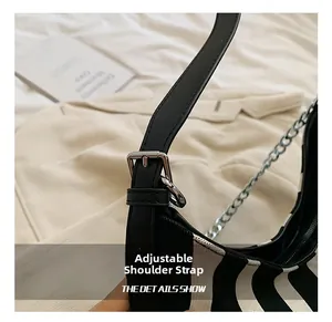 Detail showing adjustable leather shoulder strap and silver chain on striped crossbody bag
