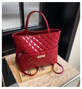 Macro shot of red quilted tote bag in patent leather finish with sleek metal logo plaque