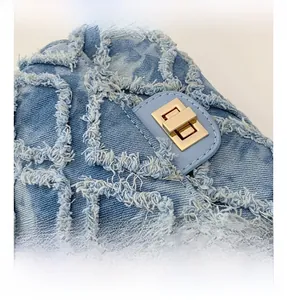 Vue macro du tissu denim effiloché avec motif matelassé et fermoir rotatif en métal doré