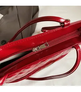 Detail of red quilted PU leather handbag featuring a smooth silver metal zipper closure