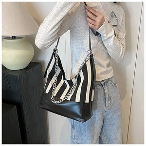 Detail of black and white striped canvas tote bag with silver chain and leather base