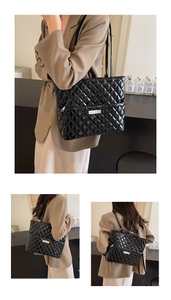 Detail of black quilted tote bag with silver logo and glossy faux leather finish