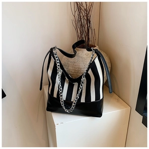 Detail of canvas striped bag featuring silver metal chain and black leather trim