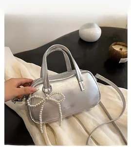 Macro detail of silver textured mini box bag with pearl bow pendant and brand engraving